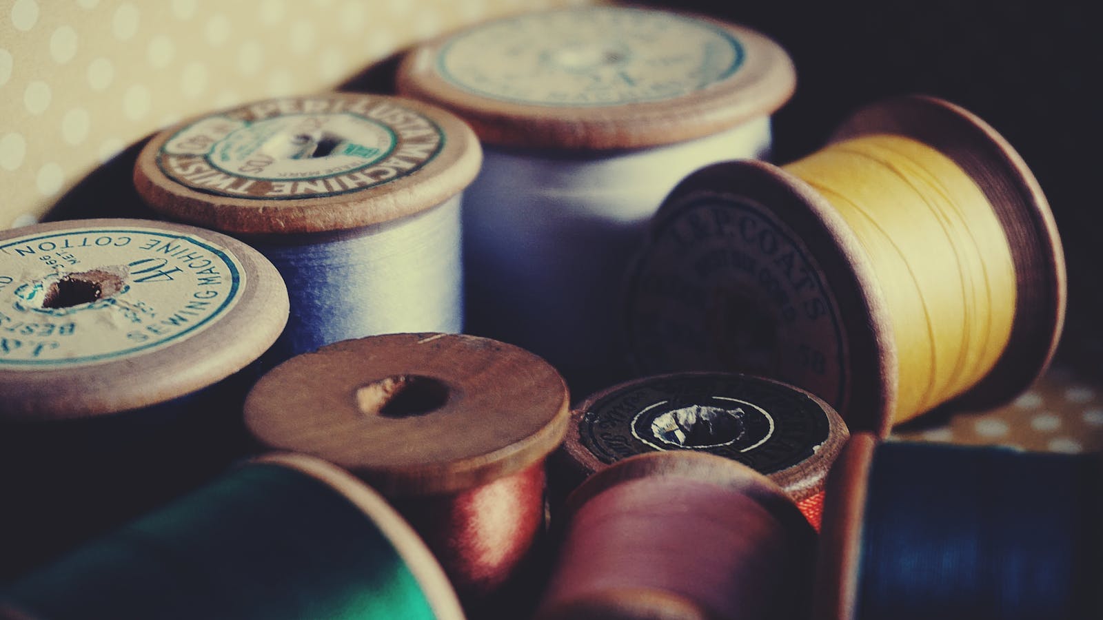 Photo by Suzy Hazelwood A close-up of vintage wooden spools displaying colorful sewing threads for crafting and tailoring.